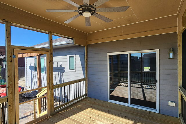 Inside a screened porch: finished ceiling with a ceiling fan, screen walls and screen door, wood deck floor, and a sliding glass door into the house